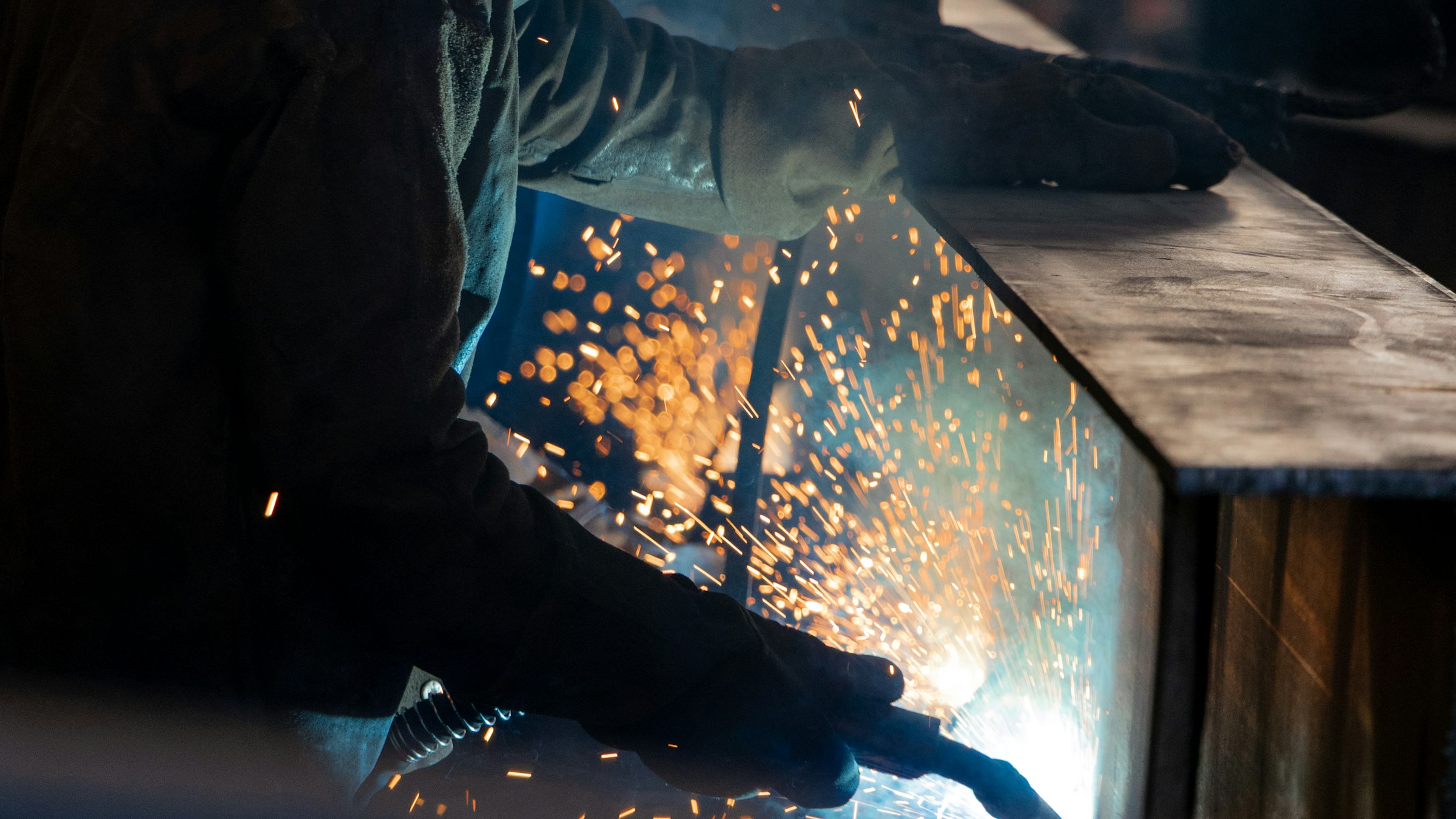 Welder at work in a fabrication workshop, sparks flying